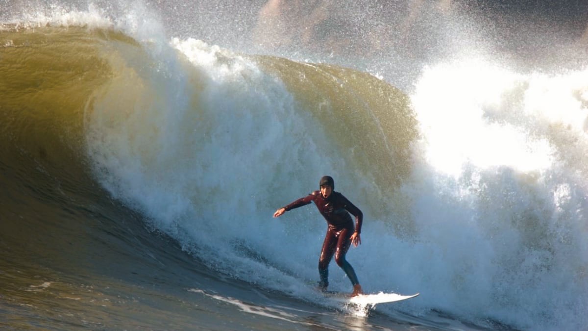 A surfer dropping into a heavy barrelling wave